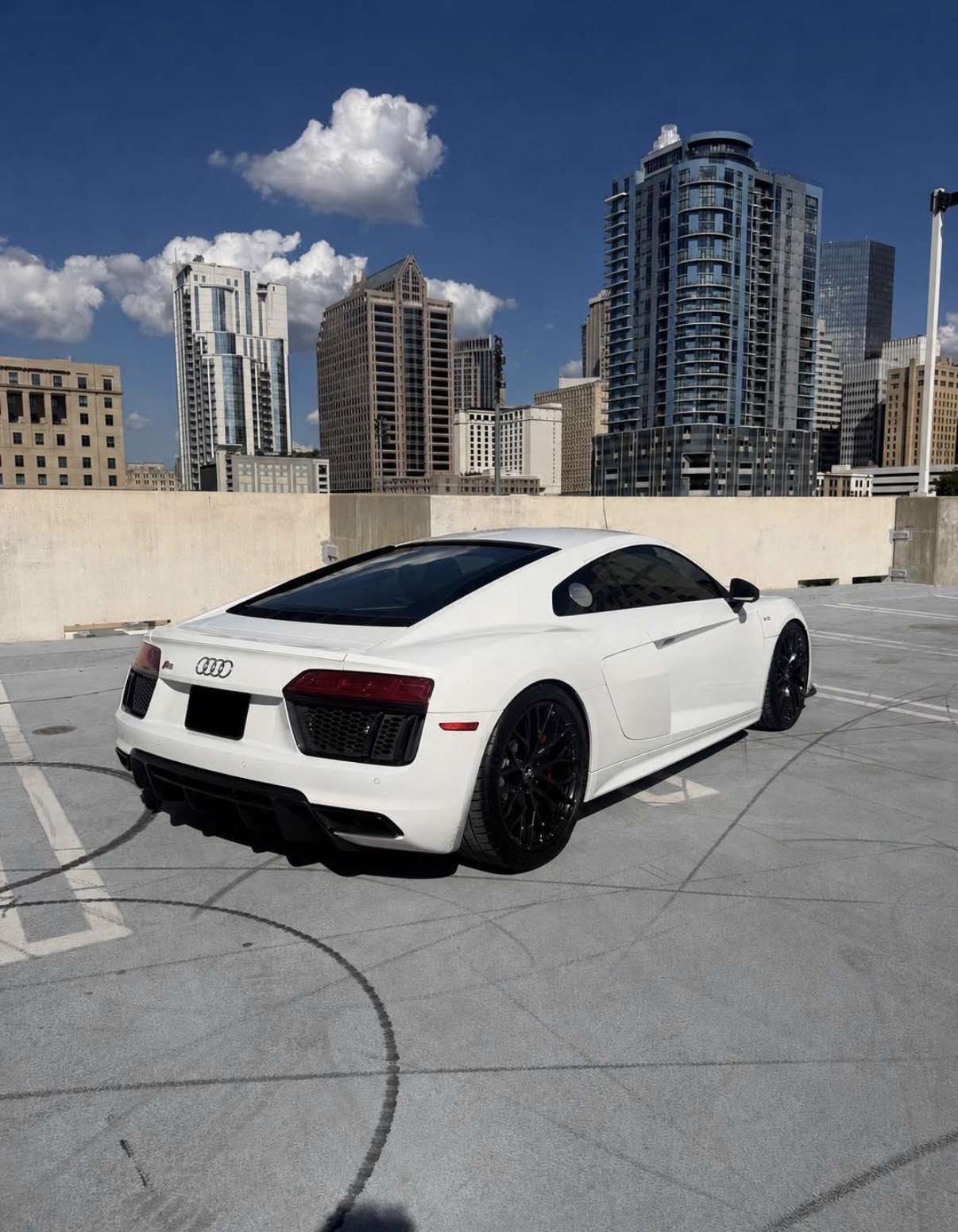 White Audi R8 on a rooftop deck with the Atlanta skyline behind