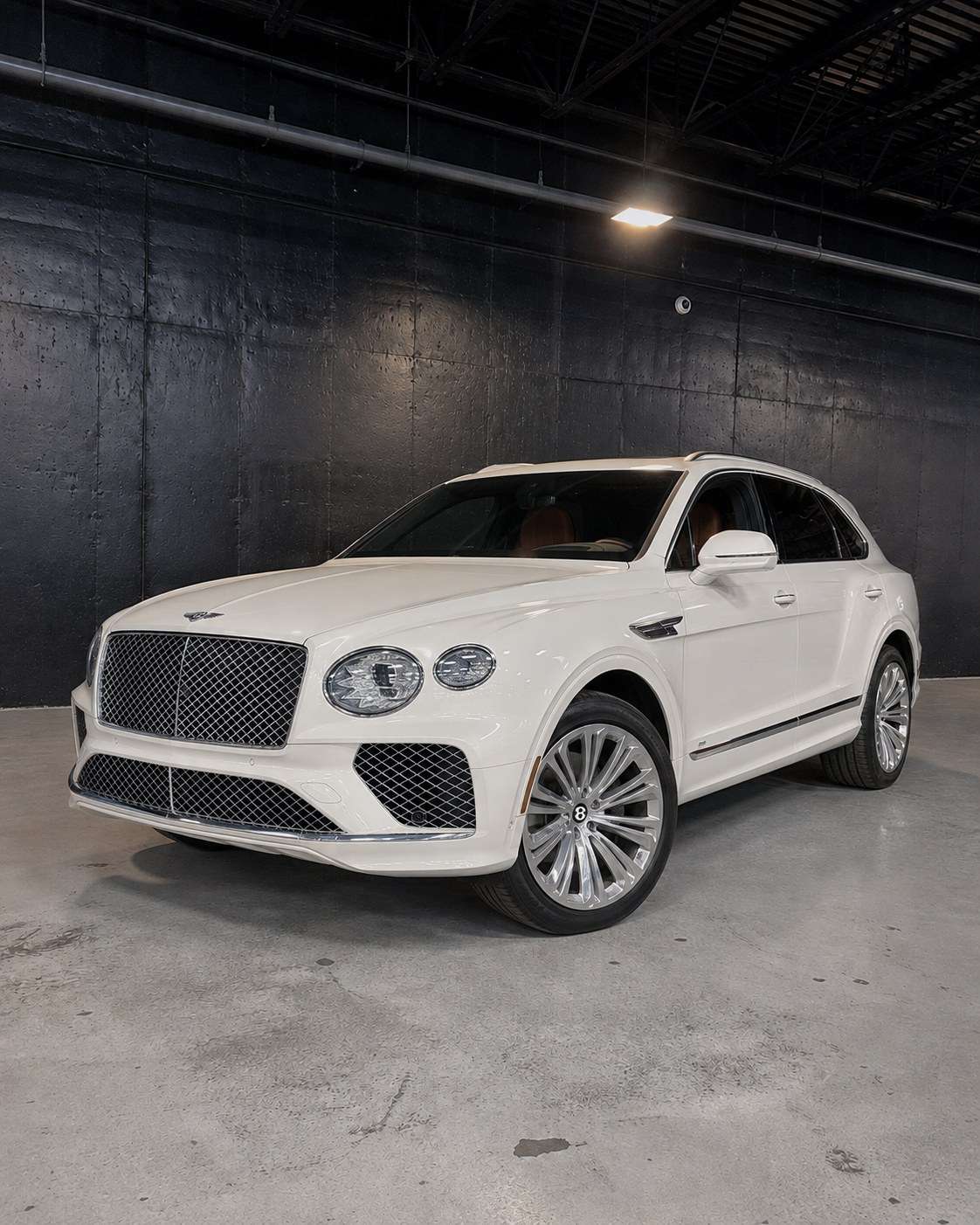 White Bentley Bentayga, front three quarter in a dark studio