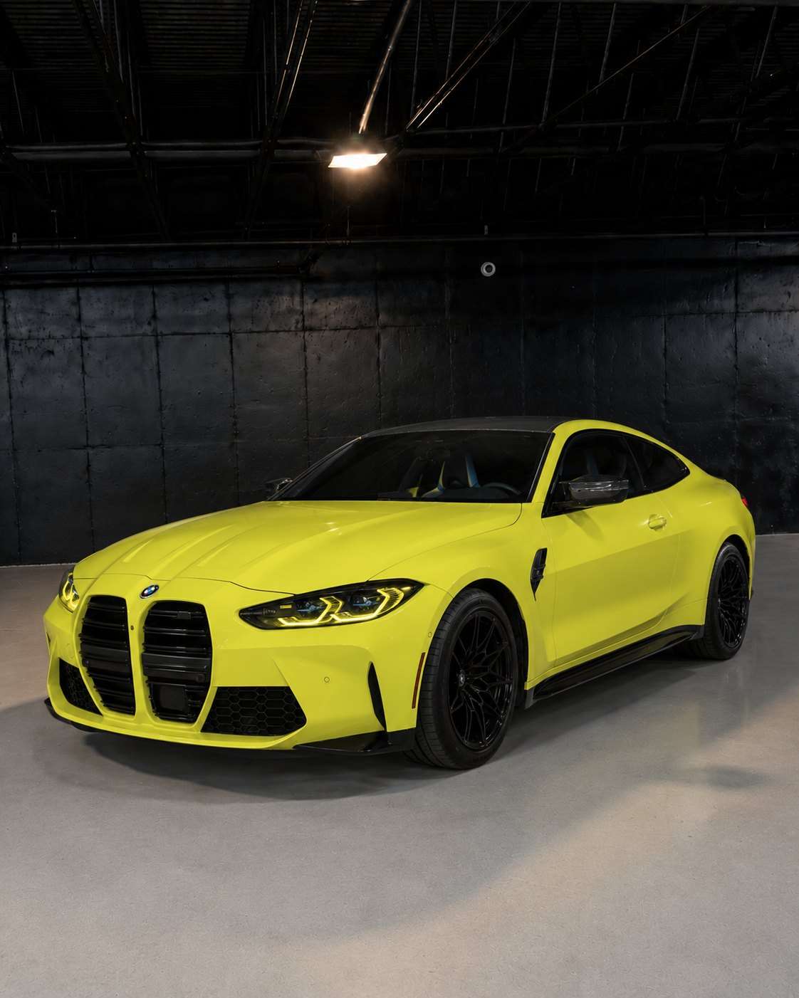 Sao Paulo Yellow BMW M4 Competition, front three quarter in a dark studio