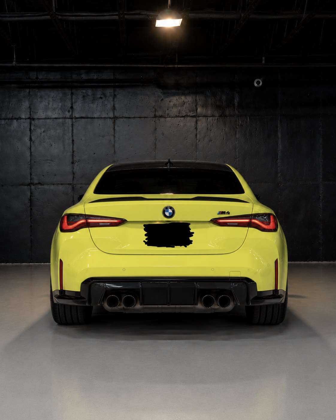 Yellow BMW M4 Competition, straight rear view with carbon diffuser