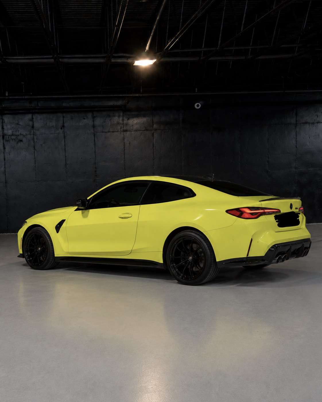 Yellow BMW M4 Competition, rear three quarter in the studio