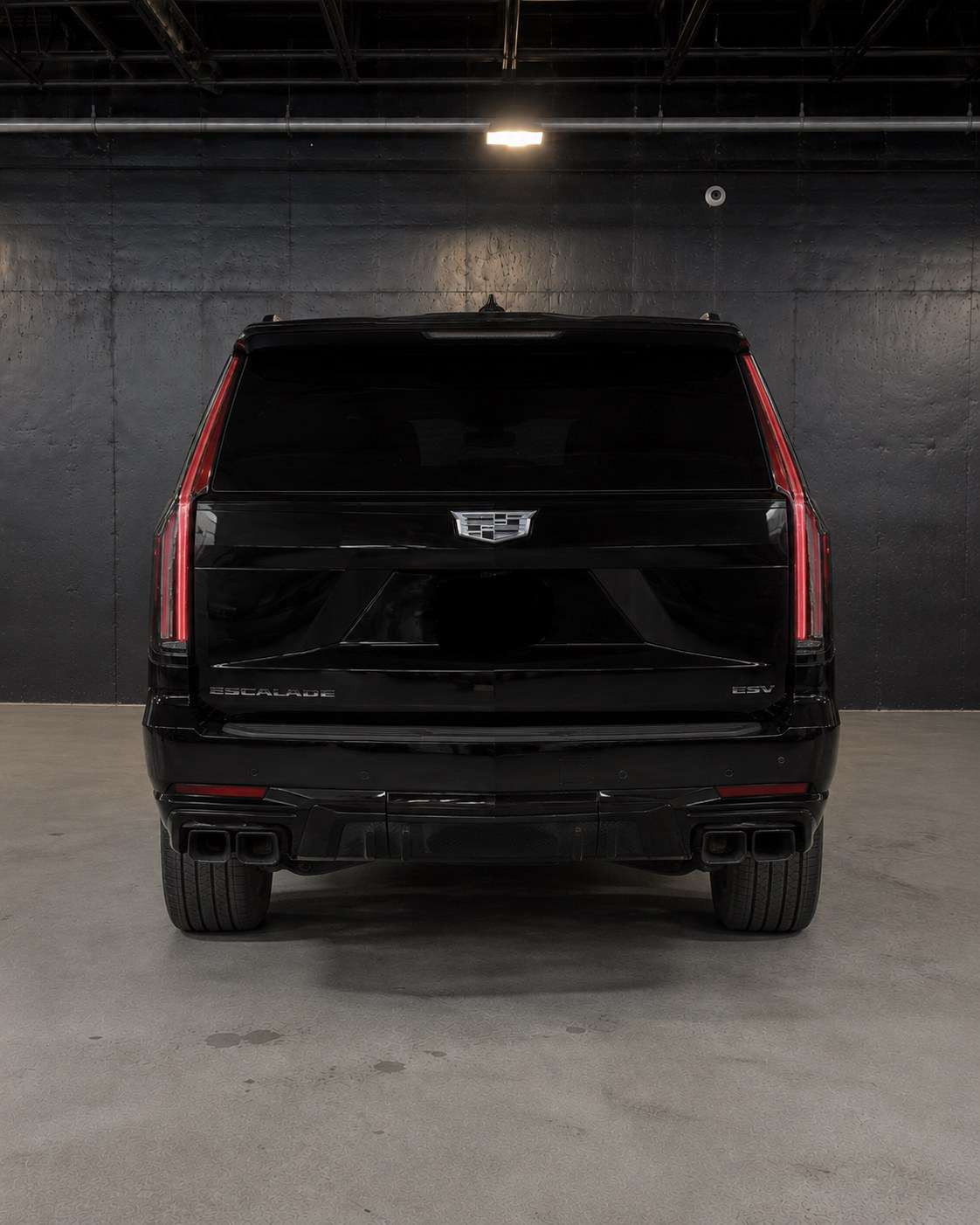 Black Cadillac Escalade ESV, straight rear view with the vertical tail lights and quad exhaust tips
