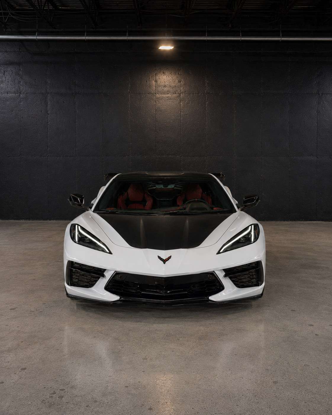 White Chevrolet Corvette C8, straight front view with the carbon hood and black splitter