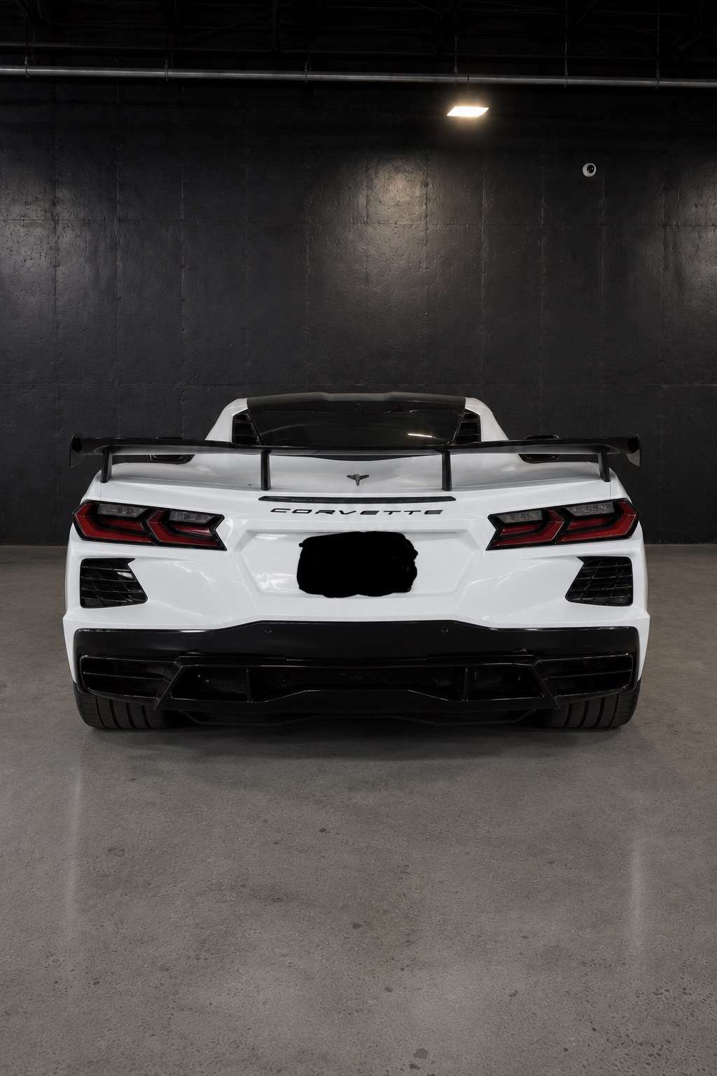 White Chevrolet Corvette C8, straight rear view with the high wing and black diffuser