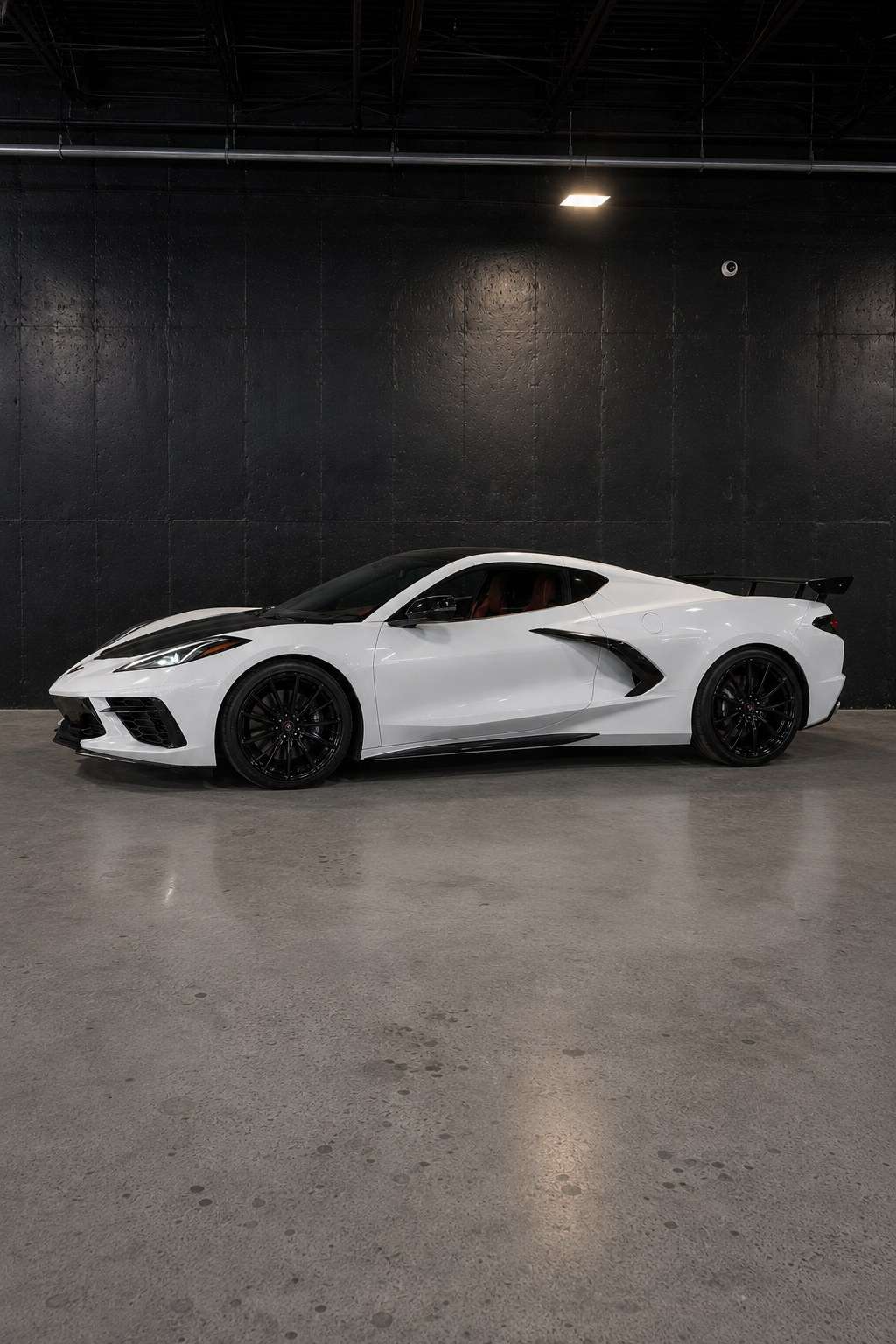 White Chevrolet Corvette C8, full side profile in the studio showing the mid-engine proportions and rear wing