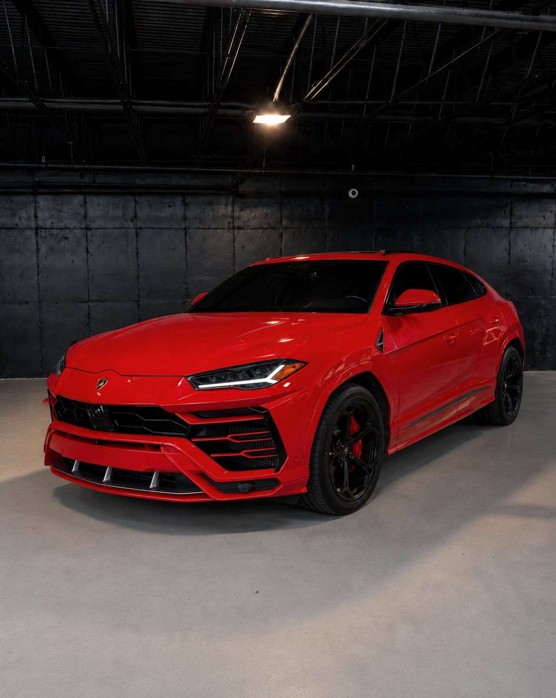 Red Lamborghini Urus, front three quarter in a dark studio