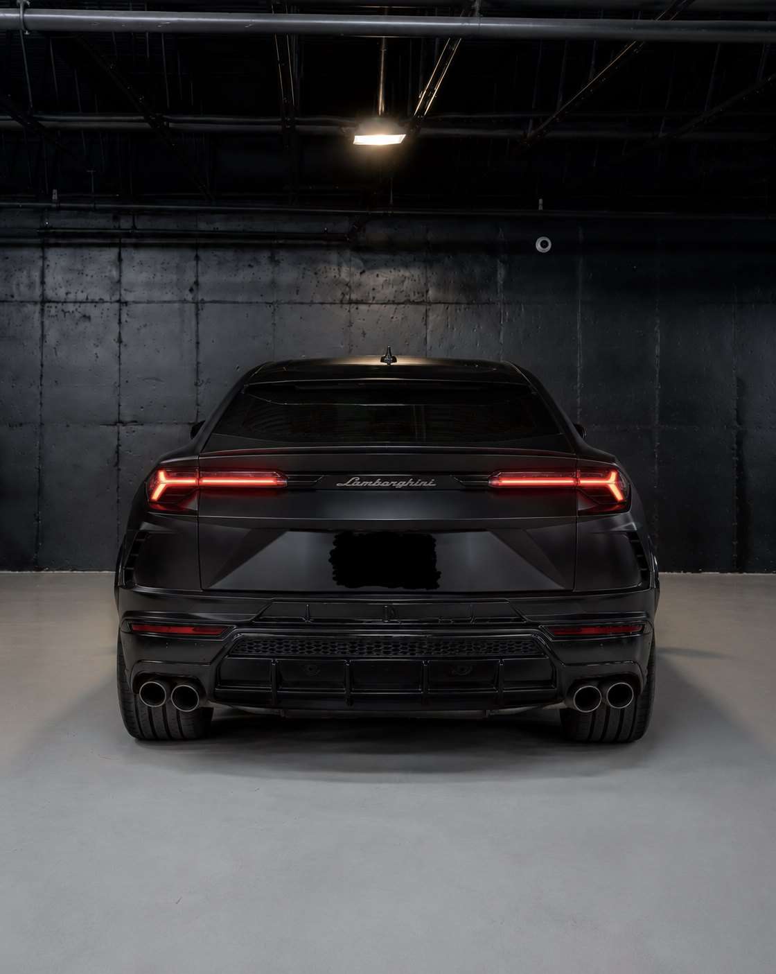 Matte black Lamborghini Urus S, straight rear view with the full width light bar