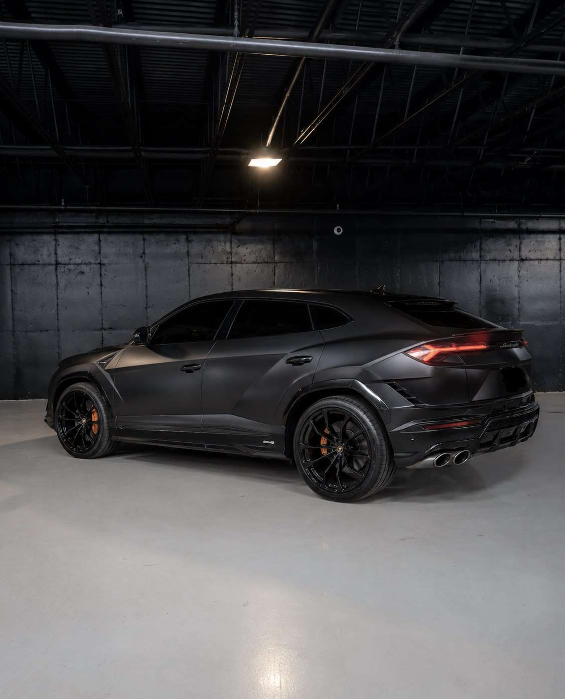 Matte black Lamborghini Urus S, rear three quarter in the studio