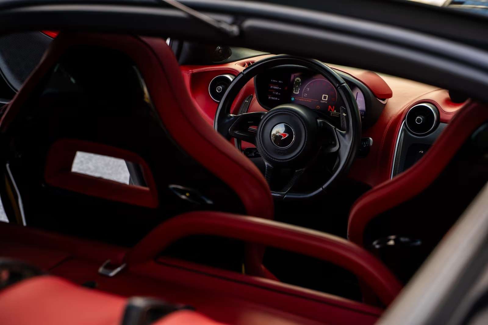 McLaren 570GT cockpit in red leather with the black steering wheel and digital cluster