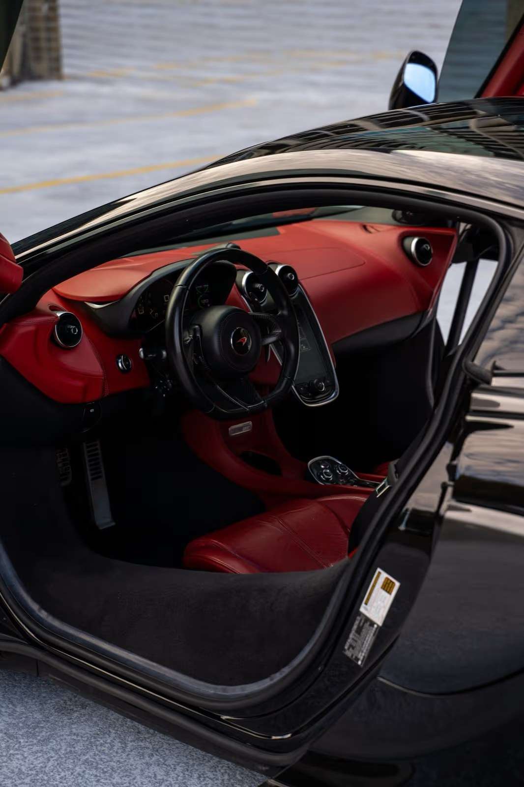 McLaren 570GT open door showing the red leather seat and dashboard