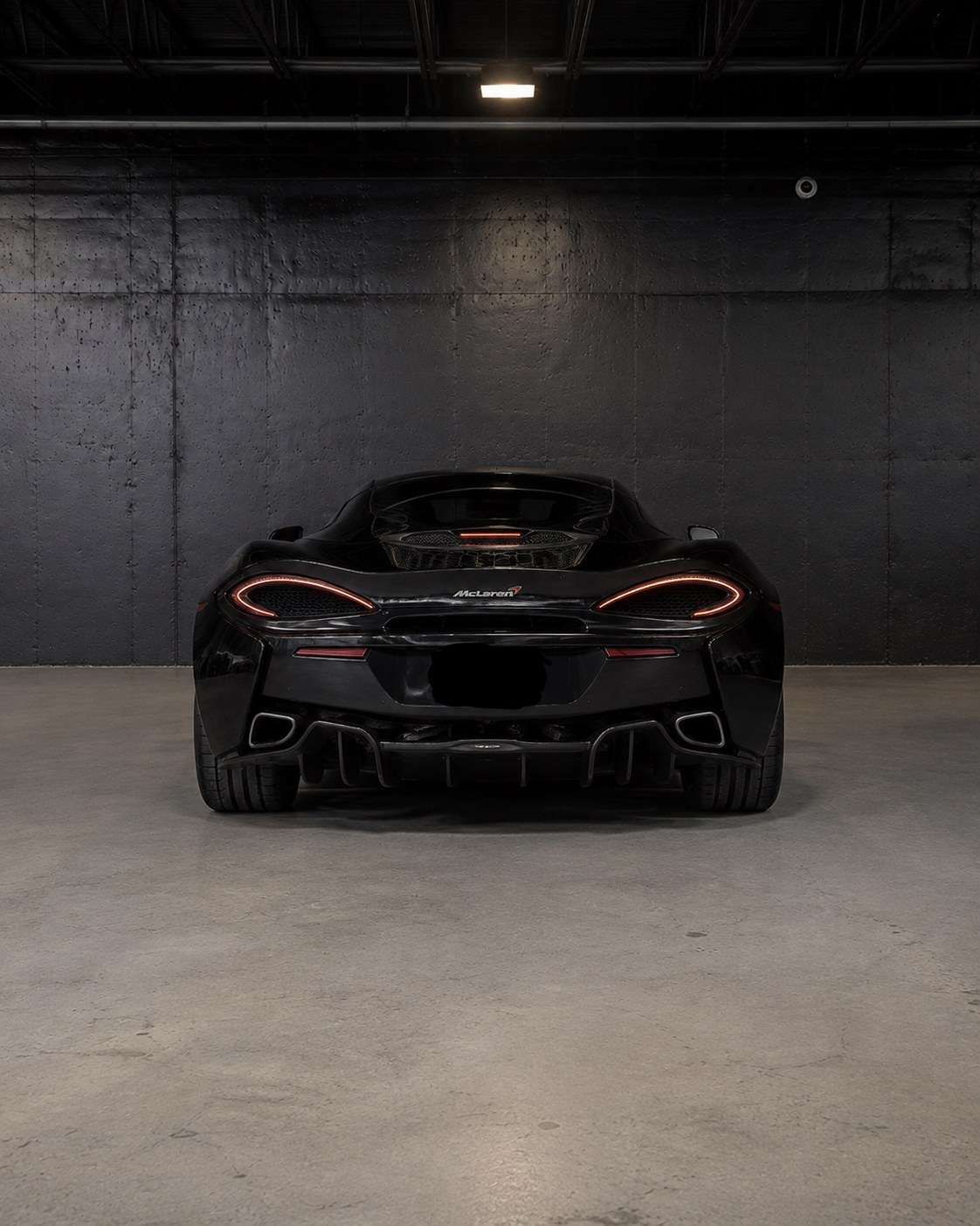 Black McLaren 570GT, straight rear view with the light bar and diffuser