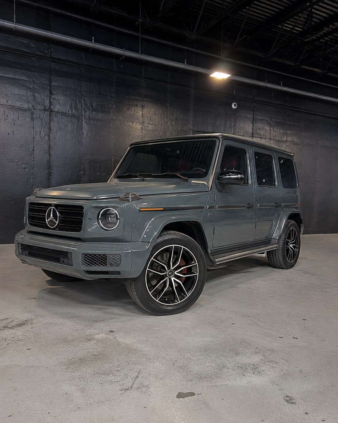 Grey Mercedes-AMG G63 with red interior, front three quarter in a dark studio