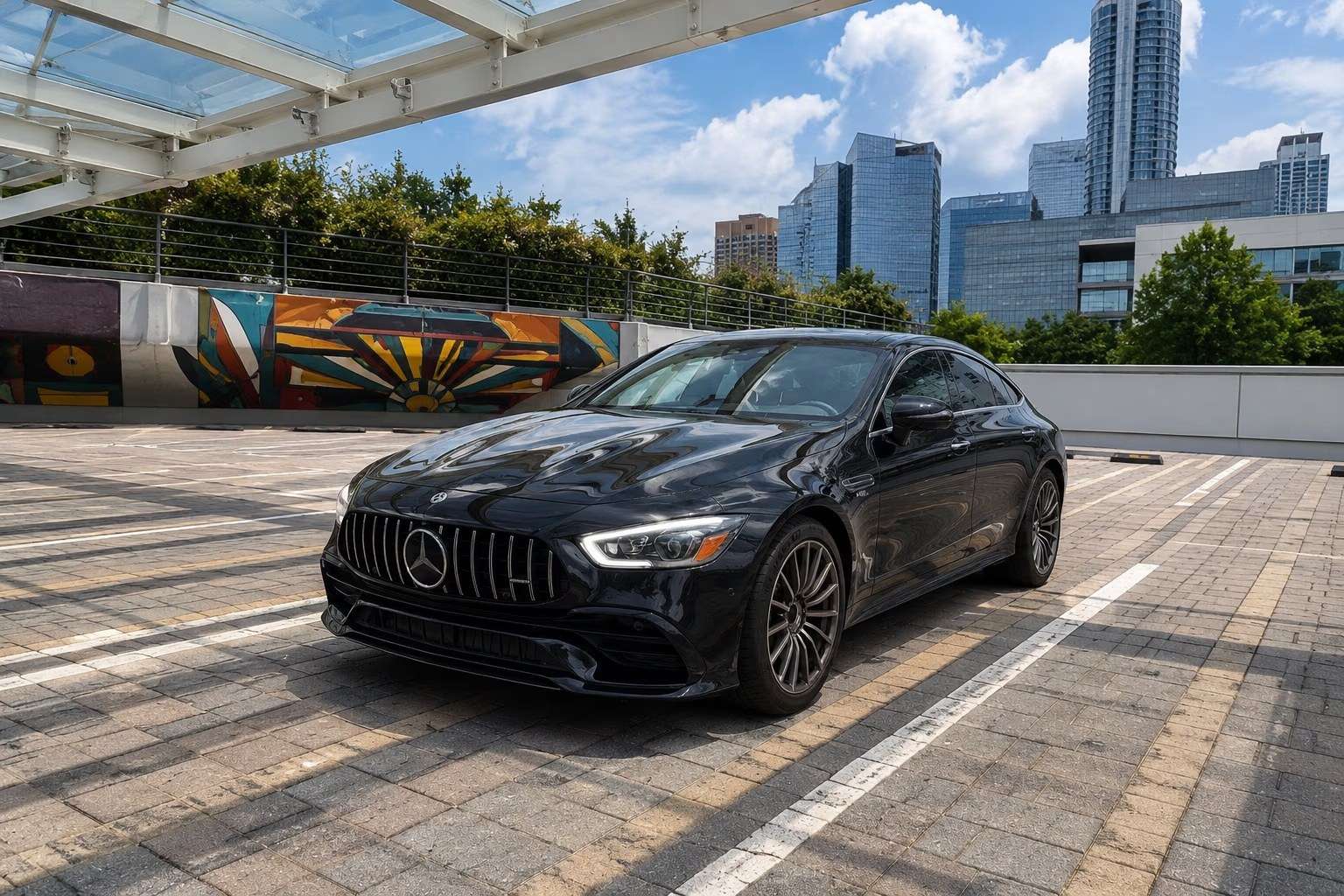 Black Mercedes-AMG GT 43 on an Atlanta parking deck with the Midtown skyline behind