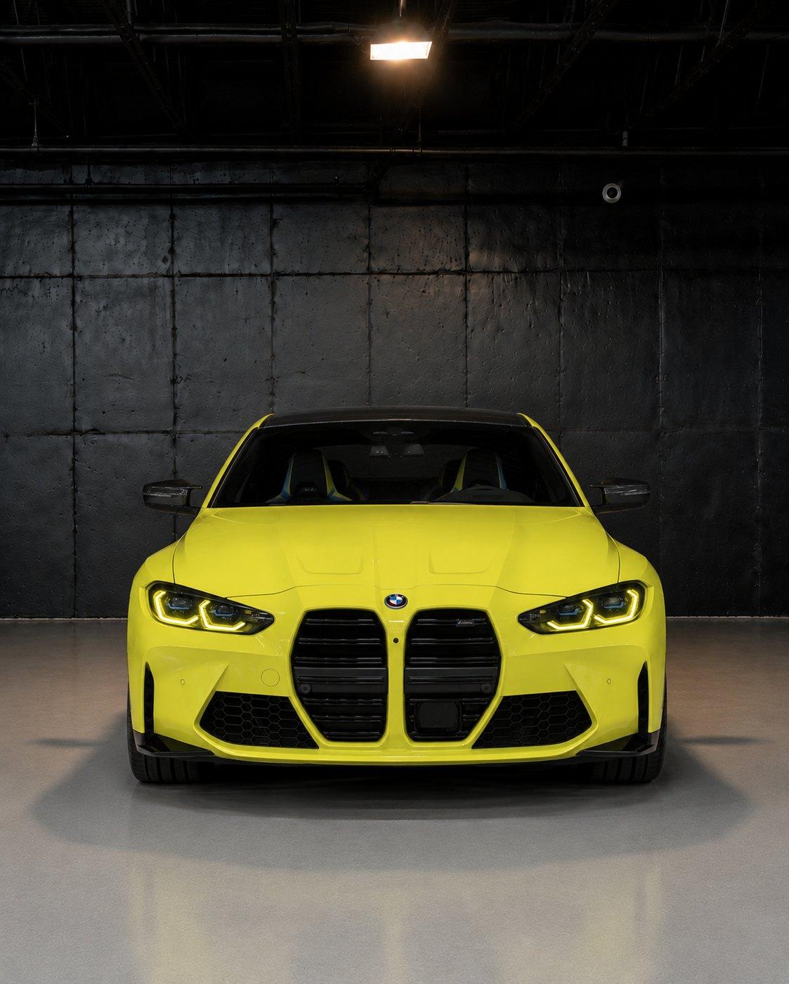 Yellow BMW M4 Competition, straight front view in the studio