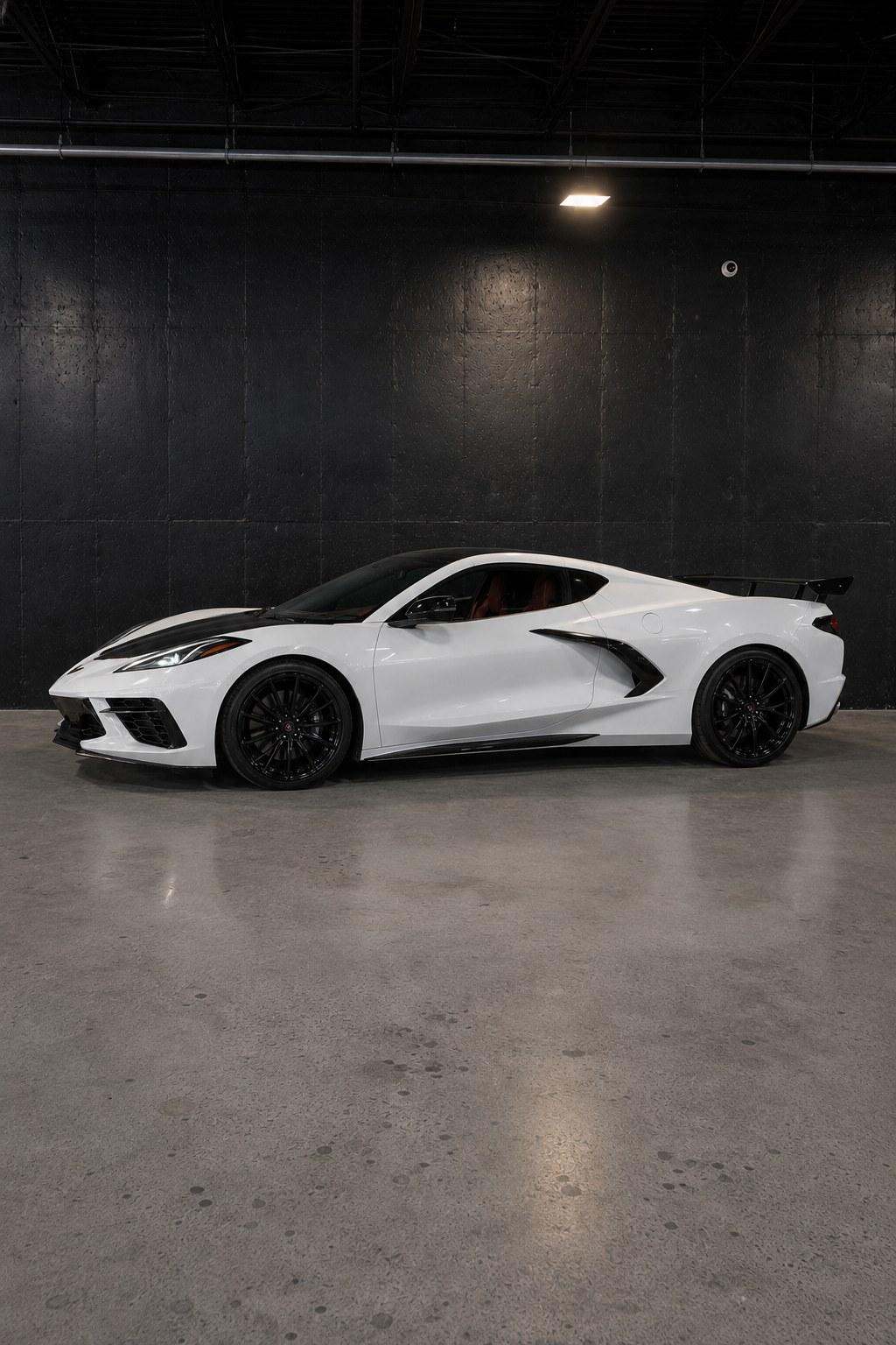 White Chevrolet Corvette C8, full side profile in the studio showing the mid-engine proportions and rear wing