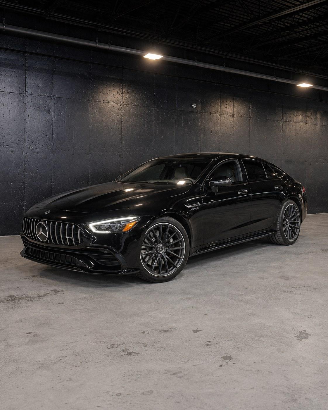 Black Mercedes-AMG GT 43 four-door with the Panamericana grille, front three quarter in a dark studio