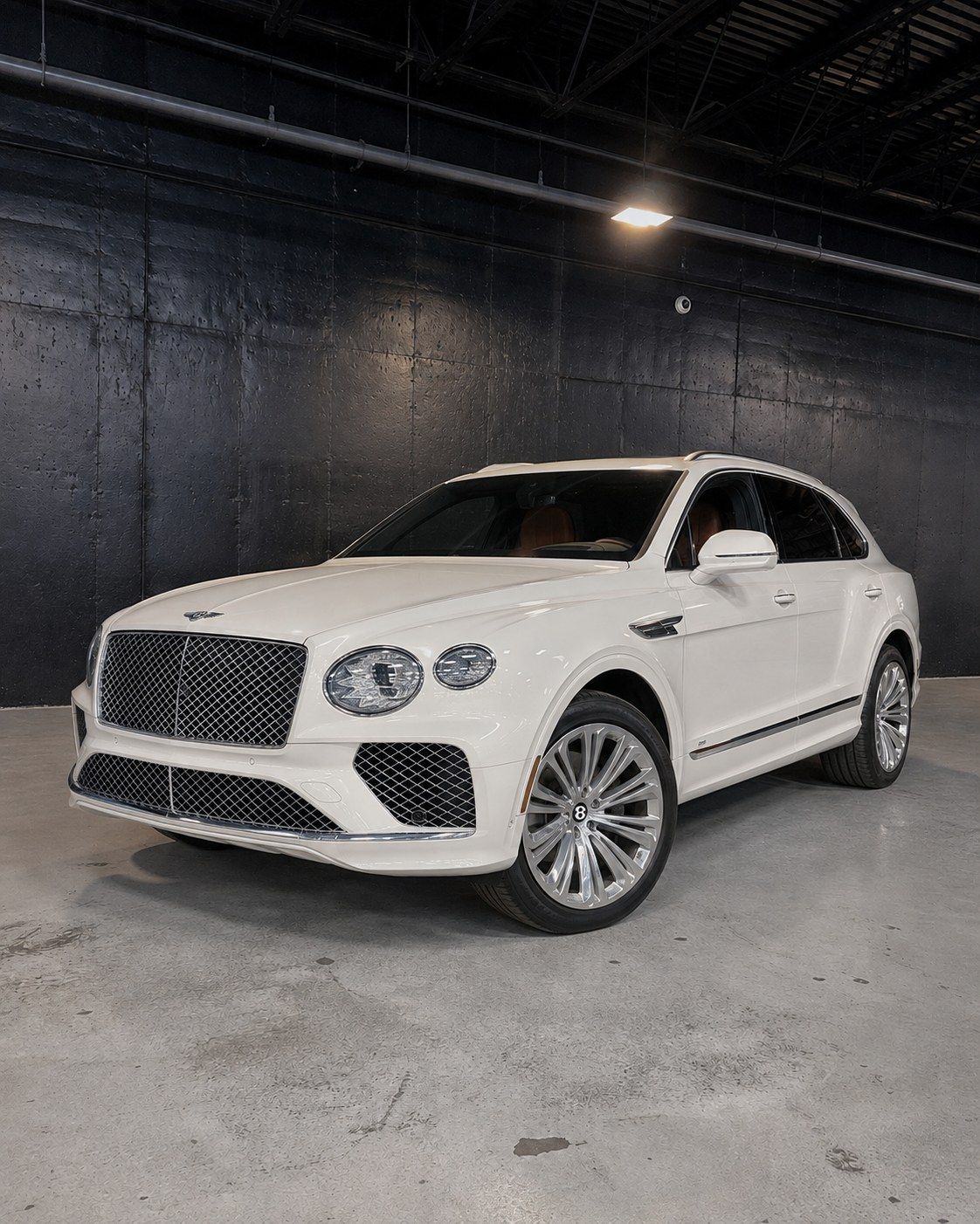 White Bentley Bentayga, front three quarter in a dark studio