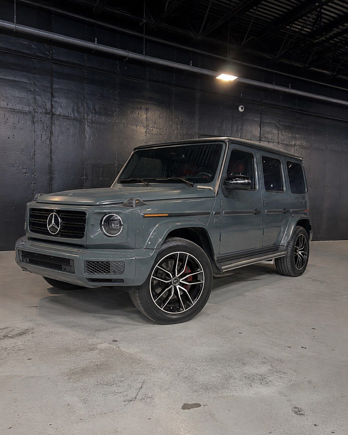 Grey Mercedes-AMG G63 with red interior, front three quarter in a dark studio