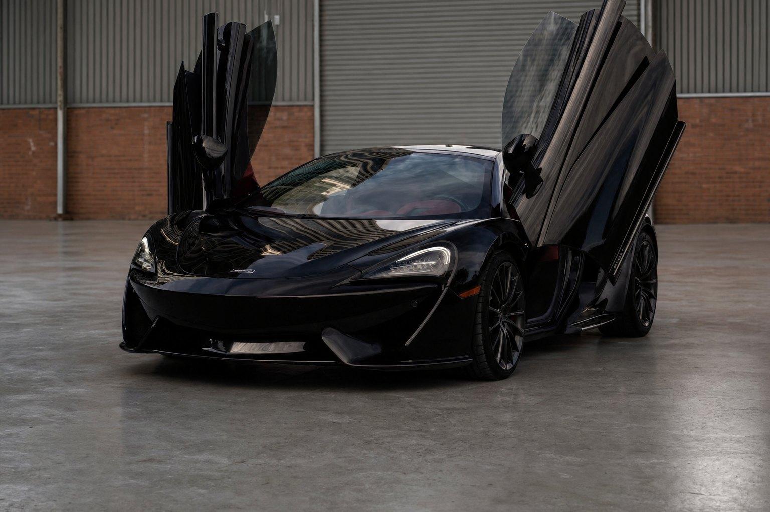 A dark exotic car parked at night outside a softly lit Atlanta restaurant entrance, warm light spilling onto wet pavement