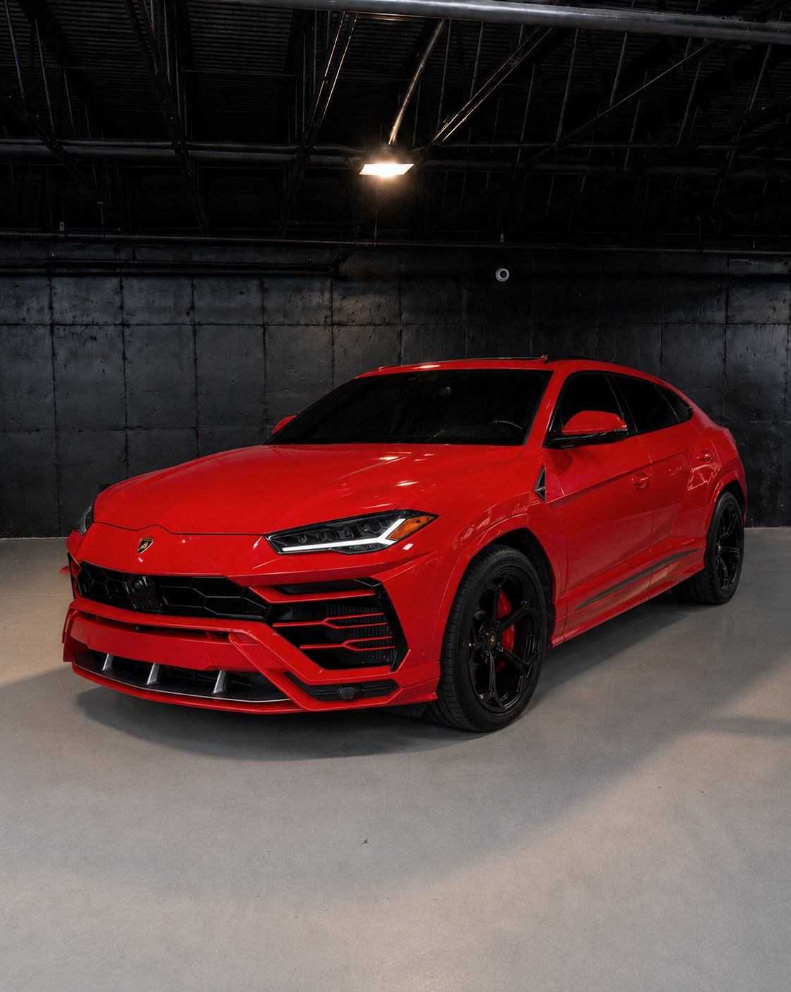 Red Lamborghini Urus, front three quarter in a dark studio