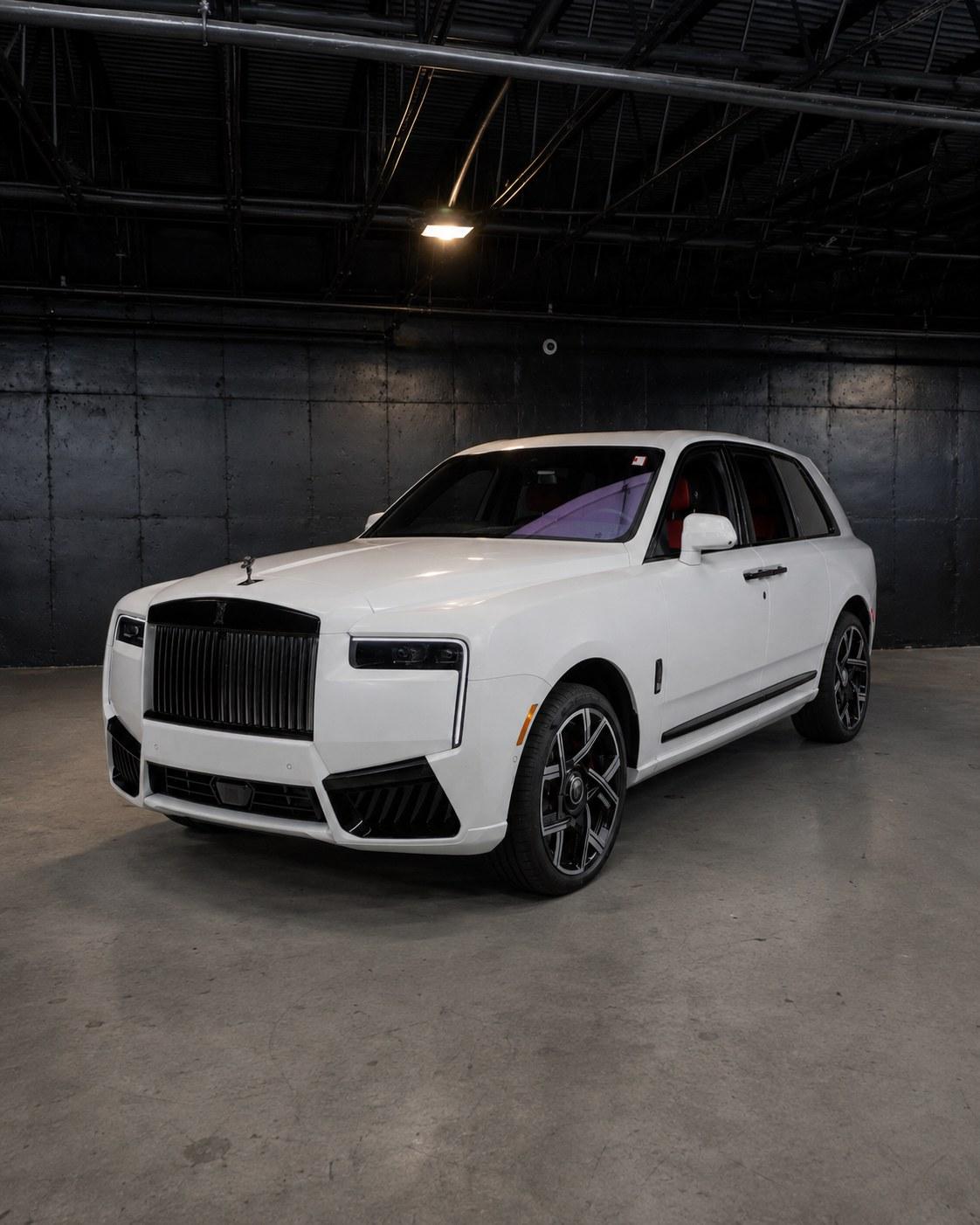 White 2027 Rolls-Royce Cullinan Black Badge with darkened grille, front three quarter in a dark studio