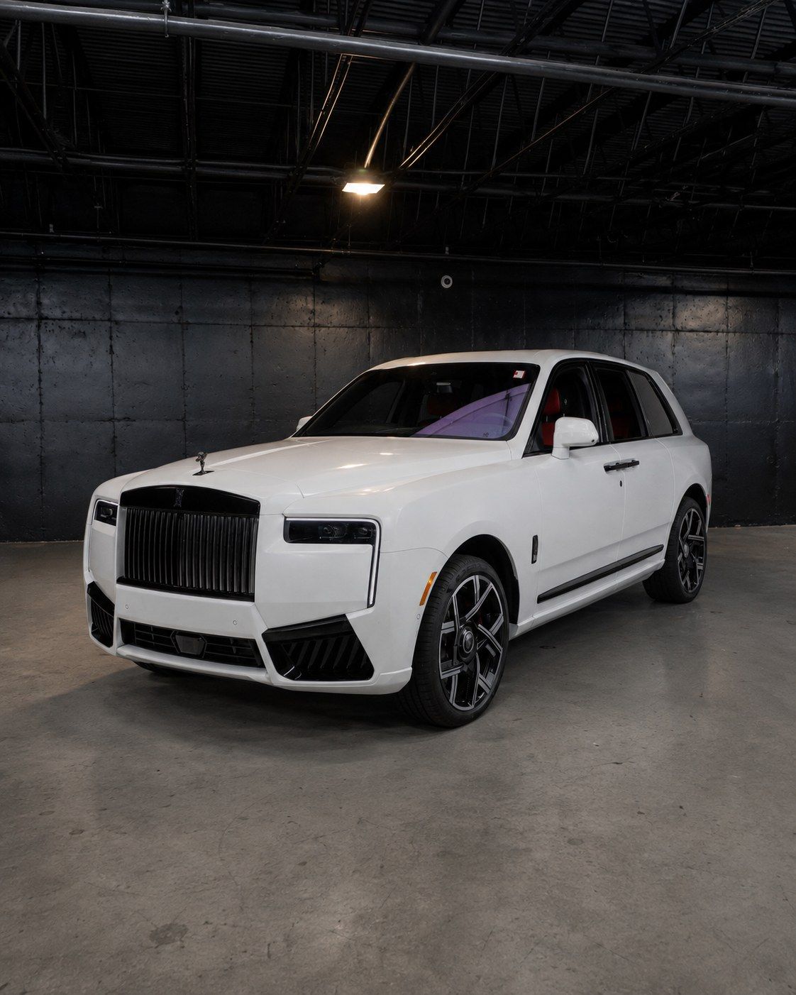 White 2027 Rolls-Royce Cullinan Black Badge with darkened grille, front three quarter in a dark studio