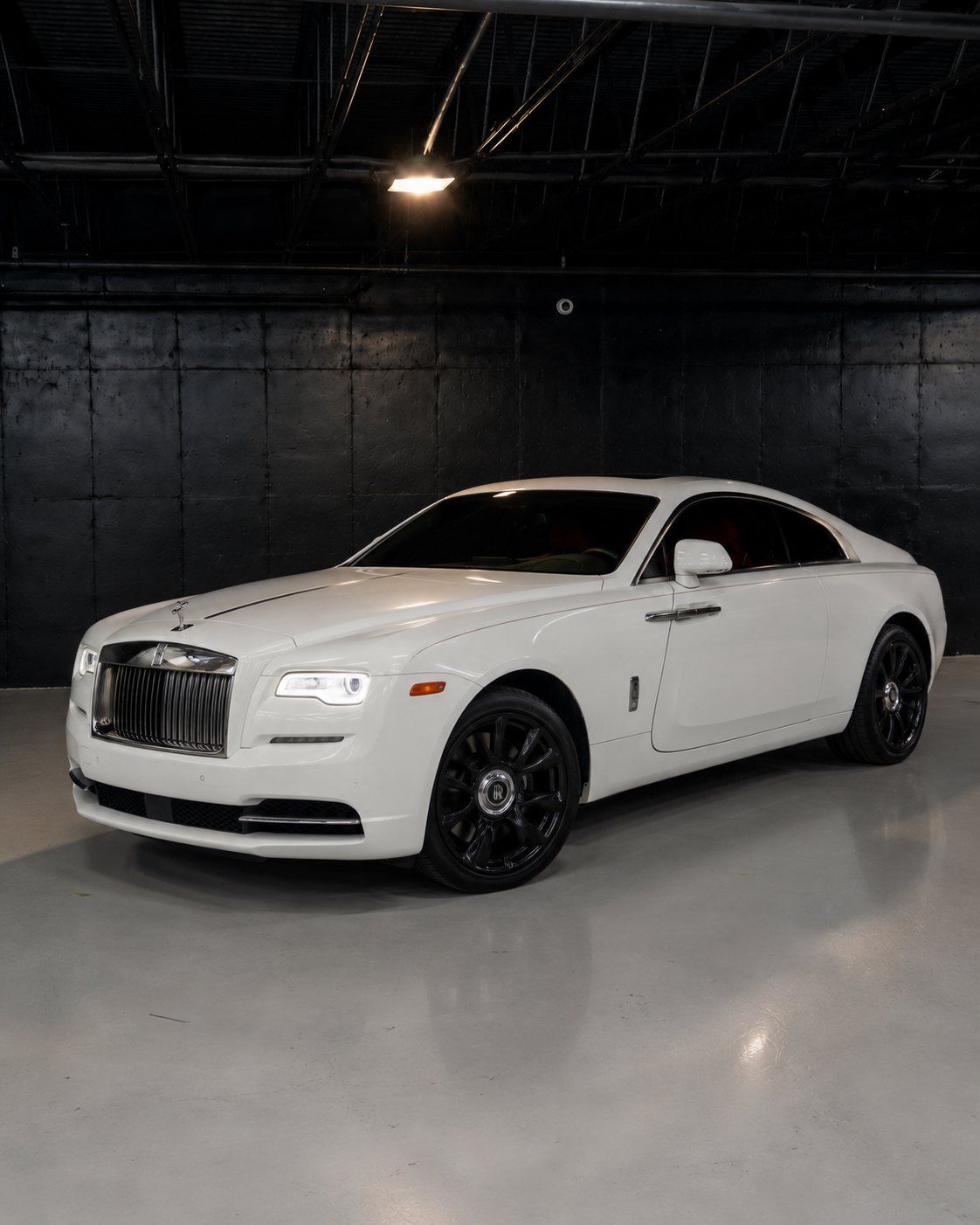 White Rolls-Royce Wraith with red interior, front three quarter in a dark studio